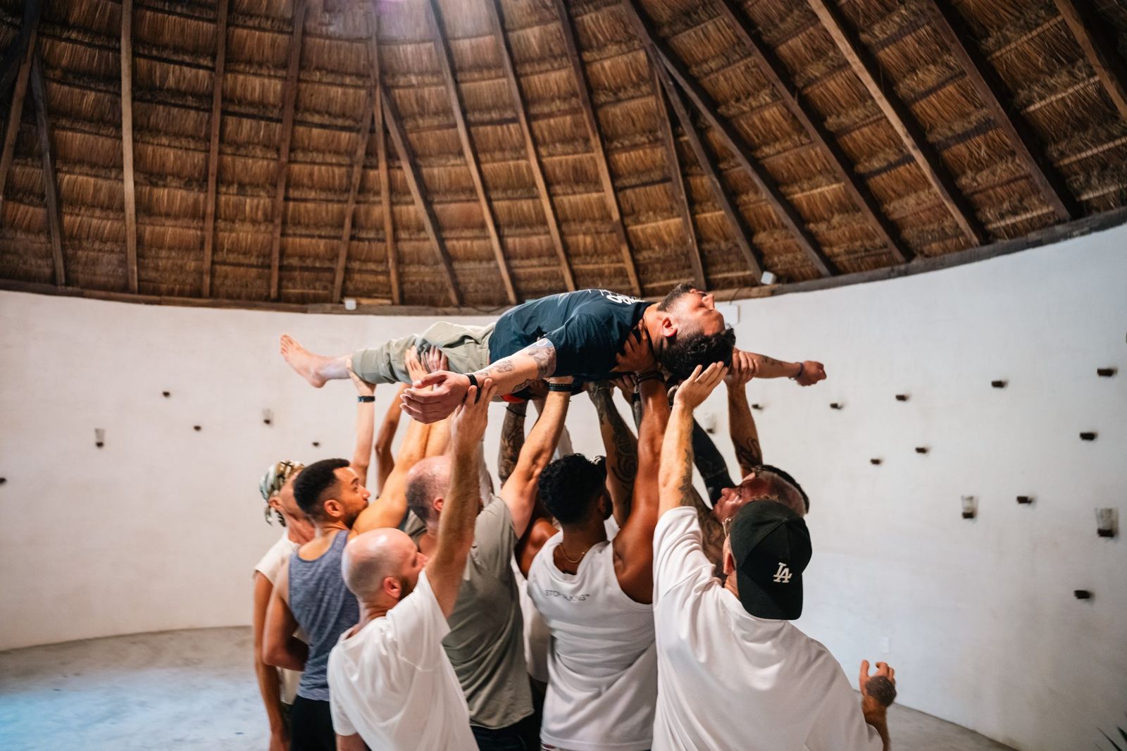 Brothers lift a man overhead in the retreat shala
